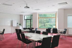 Ett ljust konferensrum i Solna med röda mattor och modern teknisk utrustning.