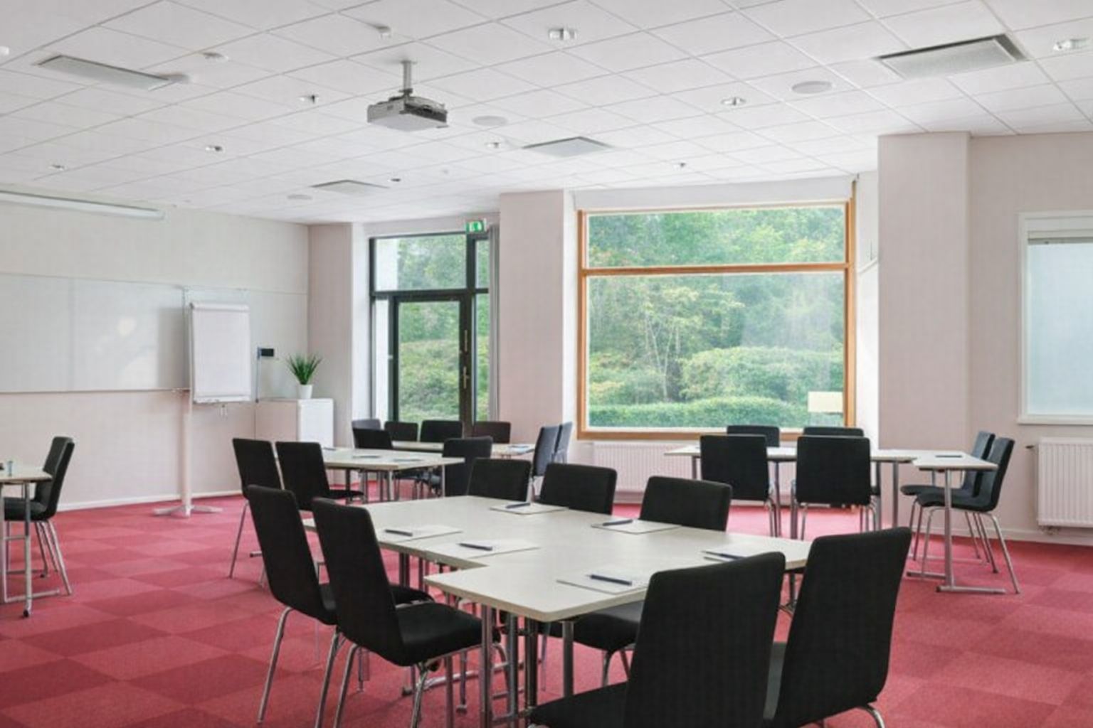 Ett ljust konferensrum i Solna med röda mattor och modern teknisk utrustning.